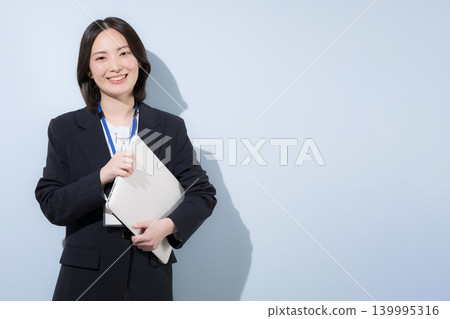 A cute, working female employee with a laptop, representing business and IT, smiling and looking at the camera. 139995316