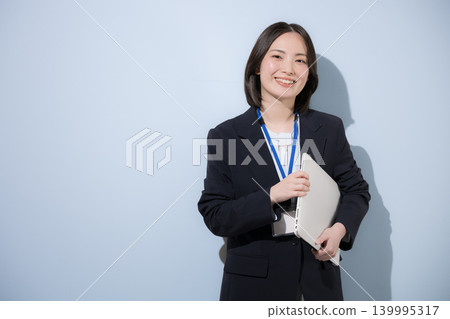 一位可愛的職業女員工，手持筆記型電腦，代表商務和IT產業，面帶微笑地看著鏡頭。 139995317