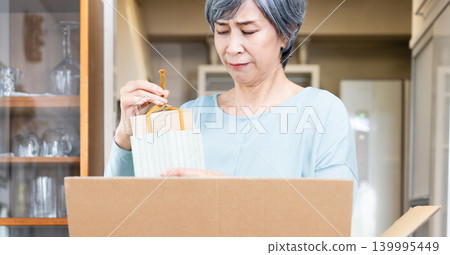 Senior woman decluttering her belongings Senior woman decluttering her belongings 139995449