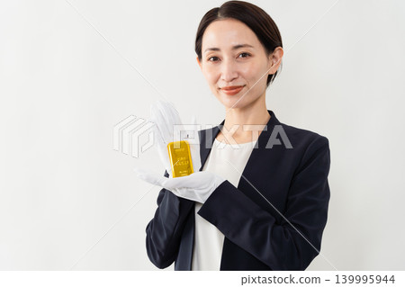 一位身著職業套裝的女士手持金錠-品牌形象 一位身著職業套裝的女士手持金錠-品牌形象 139995944