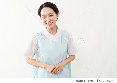 A woman wearing a light blue apron; a caregiver image. A woman wearing a light blue apron; a caregiver image. 139995980