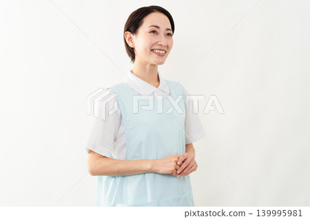 一位身穿淺藍色圍裙的女士;護理人員的形象。 一位身穿淺藍色圍裙的女士;護理人員的形象。 139995981