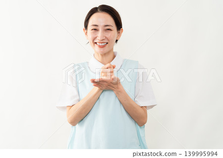 一位身穿淺藍色圍裙的女士;護理人員的形象。 一位身穿淺藍色圍裙的女士;護理人員的形象。 139995994