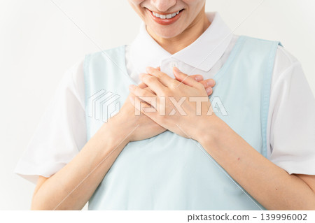 A woman wearing a light blue apron; a caregiver image. A woman wearing a light blue apron; a caregiver image. 139996002