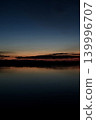 A vibrant sunset reflected on the water's edge. 139996707
