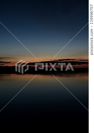 A vibrant sunset reflected on the water's edge. A vibrant sunset reflected on the water's edge. 139996707