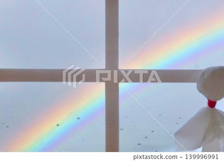 A rainbow and a teru teru bozu (weather doll) in the window after the rain. 139996991