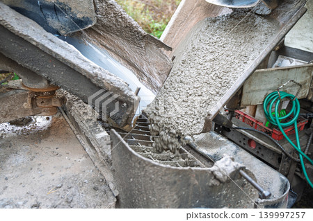 Pouring wet concrete from mixer truck into pump at construction site, industrial building and m Pouring wet concrete from mixer truck into pump at construction site, industrial building and m 139997257