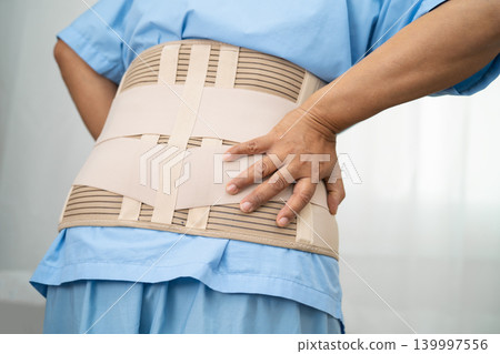 Asian lady patient wearing back pain support belt for orthopedic lumbar with walker. Asian lady patient wearing back pain support belt for orthopedic lumbar with walker. 139997556