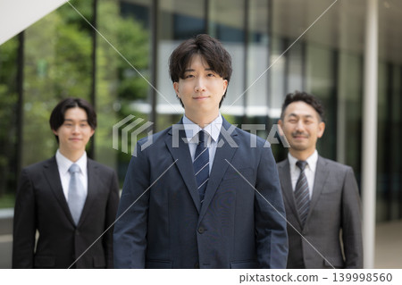 A business image of a sales organization and talent development centered around mid-career businessmen in their 30s, moving forward as a team; smiling and looking at the camera. 139998560