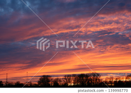 Spectacular sunset sky with vibrant orange and purple clouds over trees Spectacular sunset sky with vibrant orange and purple clouds over trees 139998770