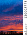Vibrant dramatic sunset sky with colorful clouds above dark forest 139998773