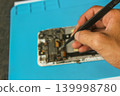 Technician Repairing Smartphone Motherboard with Precision Tweezers, Mobile Phone Repair Close Up 139998780