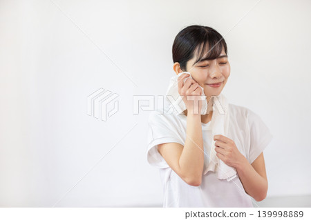 一位年輕的日本女子麵帶微笑，用毛巾擦了擦額頭的汗。 139998889