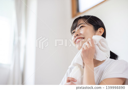 一位年輕的日本女子麵帶微笑，用毛巾擦了擦額頭的汗。 139998890