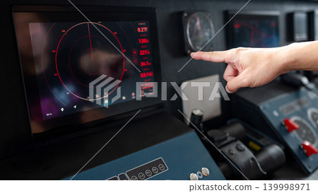 Captain hand pointing at marine radar monitor on boat dashboard 139998971