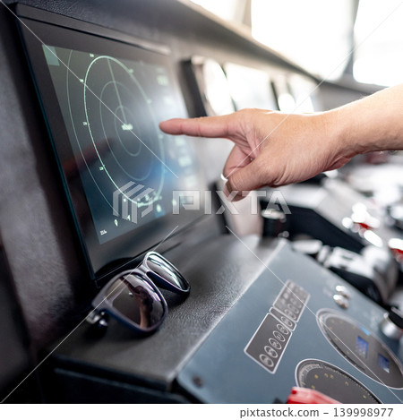 Captain hand pointing at marine radar monitor on boat dashboard Captain hand pointing at marine radar monitor on boat dashboard 139998977