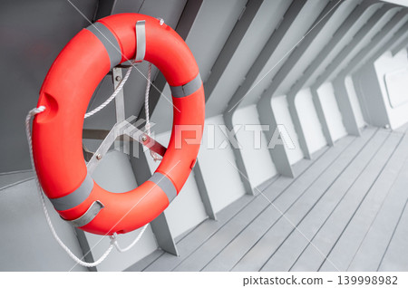 Orange lifebuoy or life preserver ring hanging on side wall of steel boat 139998982