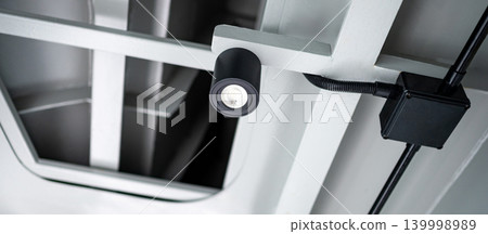 Modern black cylinder LED spotlight or cylindrical downlight hanging on the ceiling 139998989