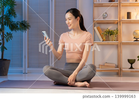 一位身穿瑜珈服的女子在夜裡看著她的智慧型手機。 139999163