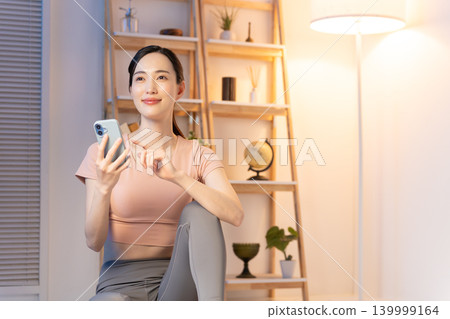 一位身穿瑜珈服的女子在夜裡看著她的智慧型手機。 139999164