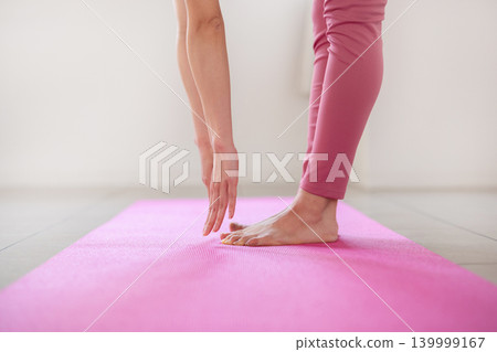 特寫鏡頭拍攝一位女性在瑜珈墊上做前屈伸展動作時，她的指尖和腳。 139999167