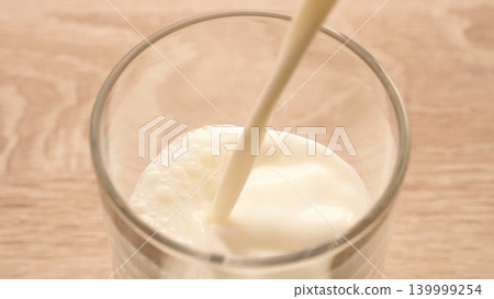 Milk Pouring Into Glass Cup In High Angle View, Lactose Free Dairy Nutrition And Healthy Beverage Concept Milk Pouring Into Glass Cup In High Angle View, Lactose Free Dairy Nutrition And Healthy Beverage Concept 139999254