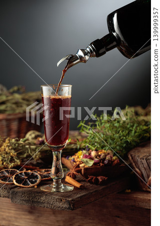 Herbal bitter liqueur is poured from a vintage bottle into a glass. Herbal bitter liqueur is poured from a vintage bottle into a glass. 139999357
