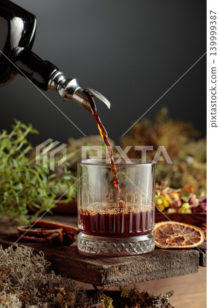 Herbal bitter liqueur is poured from a vintage bottle into a glass. Herbal bitter liqueur is poured from a vintage bottle into a glass. 139999387