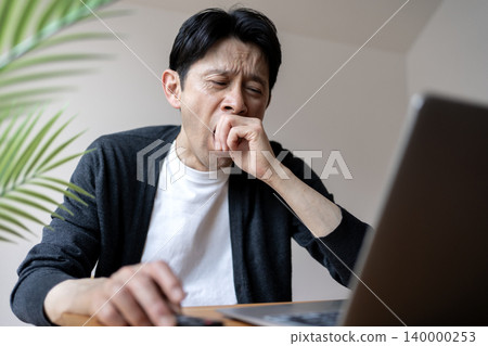 A middle-aged man working while fighting off sleepiness A middle-aged man working while fighting off sleepiness 140000253