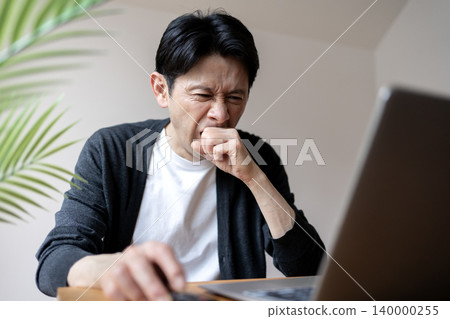 A middle-aged man working while fighting off sleepiness 140000255