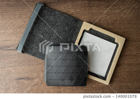Handmade black wallet made of genuine leather on a wooden background. Close-up, top view. Handmade black wallet made of genuine leather on a wooden background. Close-up, top view. 140001078