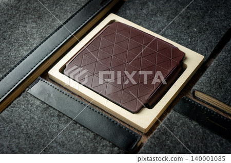 Handmade red brown wallet made of genuine leather on a wooden background. Close-up, top view. Handmade red brown wallet made of genuine leather on a wooden background. Close-up, top view. 140001085