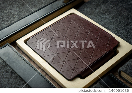 Handmade red brown wallet made of genuine leather on a wooden background. Close-up, top view. Handmade red brown wallet made of genuine leather on a wooden background. Close-up, top view. 140001086