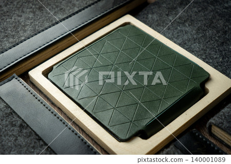 Handmade green wallet made of genuine leather on a wooden background. Close-up, top view. Handmade green wallet made of genuine leather on a wooden background. Close-up, top view. 140001089