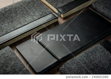 Handmade black wallet made of genuine leather on a wooden background. Close-up, top view. Handmade black wallet made of genuine leather on a wooden background. Close-up, top view. 140001090