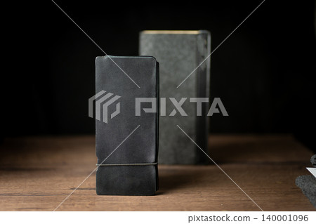 Handmade black wallet made of genuine leather on a wooden background. Close-up, top view. Handmade black wallet made of genuine leather on a wooden background. Close-up, top view. 140001096