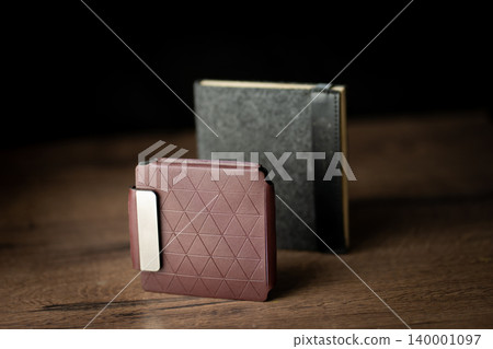 Handmade red brown wallet made of genuine leather on a wooden background. Close-up, top view. Handmade red brown wallet made of genuine leather on a wooden background. Close-up, top view. 140001097