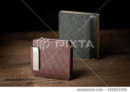 Handmade red brown wallet made of genuine leather on a wooden background. Close-up, top view. Handmade red brown wallet made of genuine leather on a wooden background. Close-up, top view. 140001098