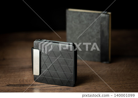 Handmade black wallet made of genuine leather on a wooden background. Close-up, top view. Handmade black wallet made of genuine leather on a wooden background. Close-up, top view. 140001099