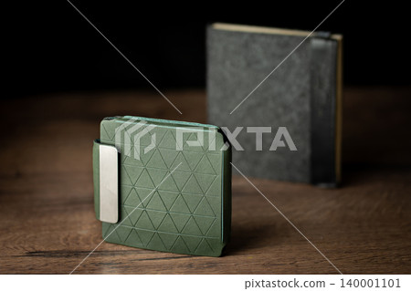Handmade green wallet made of genuine leather on a wooden background. Close-up, top view. Handmade green wallet made of genuine leather on a wooden background. Close-up, top view. 140001101