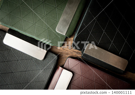 Handmade black wallet made of genuine leather on a wooden background. Close-up, top view. Handmade black wallet made of genuine leather on a wooden background. Close-up, top view. 140001111