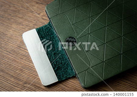 Handmade green wallet made of genuine leather on a wooden background. Close-up, top view. Handmade green wallet made of genuine leather on a wooden background. Close-up, top view. 140001155
