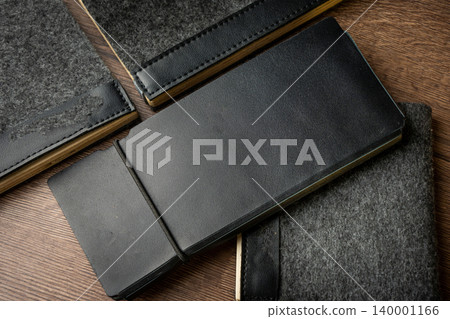Handmade black wallet made of genuine leather on a wooden background. Close-up, top view. 140001166
