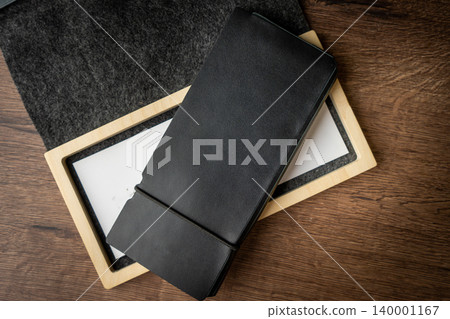 Handmade black wallet made of genuine leather on a wooden background. Close-up, top view. Handmade black wallet made of genuine leather on a wooden background. Close-up, top view. 140001167
