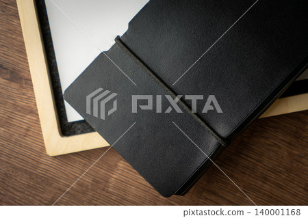 Handmade black wallet made of genuine leather on a wooden background. Close-up, top view. Handmade black wallet made of genuine leather on a wooden background. Close-up, top view. 140001168