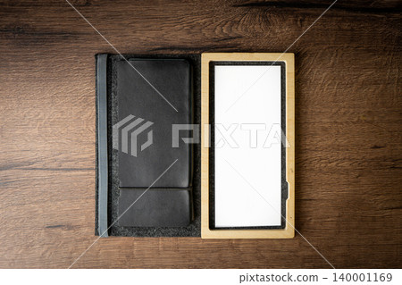 Handmade black wallet made of genuine leather on a wooden background. Close-up, top view. Handmade black wallet made of genuine leather on a wooden background. Close-up, top view. 140001169