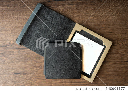 Handmade black wallet made of genuine leather on a wooden background. Close-up, top view. 140001177