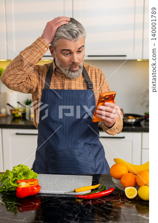 Middle-aged man shocked by bad news on smartphone in home kitchen after sudden internet message loss Middle-aged man shocked by bad news on smartphone in home kitchen after sudden internet message loss 140001789
