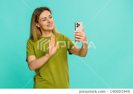 Woman waving hand while talking on smartphone video call smiling during happy online conversation 140001949